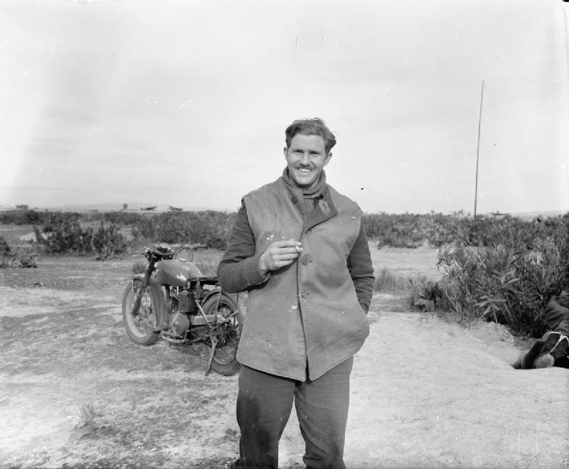 Squadron_Leader_J_J_le_Roux,_No._111_Squadron_RAF,_standing_in_front_of_his_motorcycle_at_Souk_el_Khemis_._CNA159